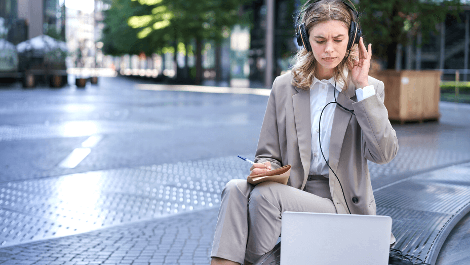 Businesswoman looking perplexed at laptop, taking notes in her notebook, attending online work